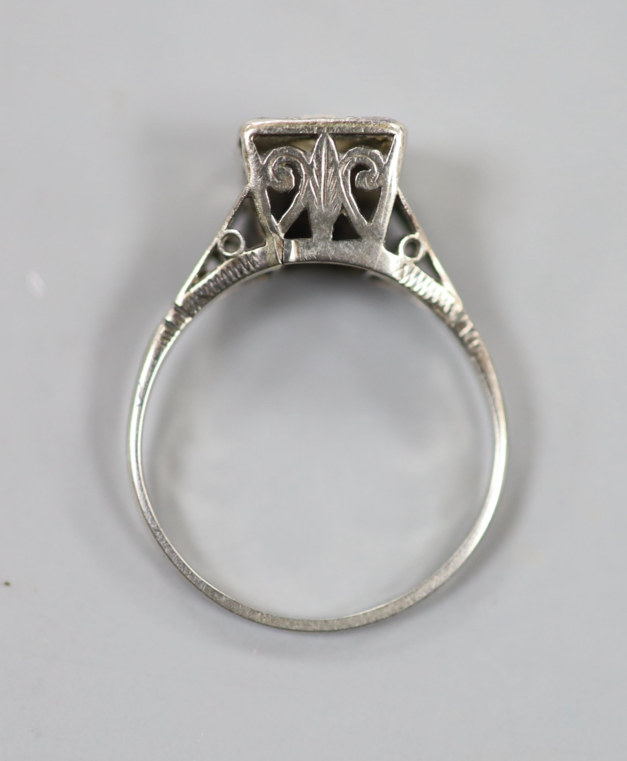 A 1920's/1930's white metal and single stone round cut diamond set square ring, with diamond set corners, size O/P, gross weight 2.9 grams.